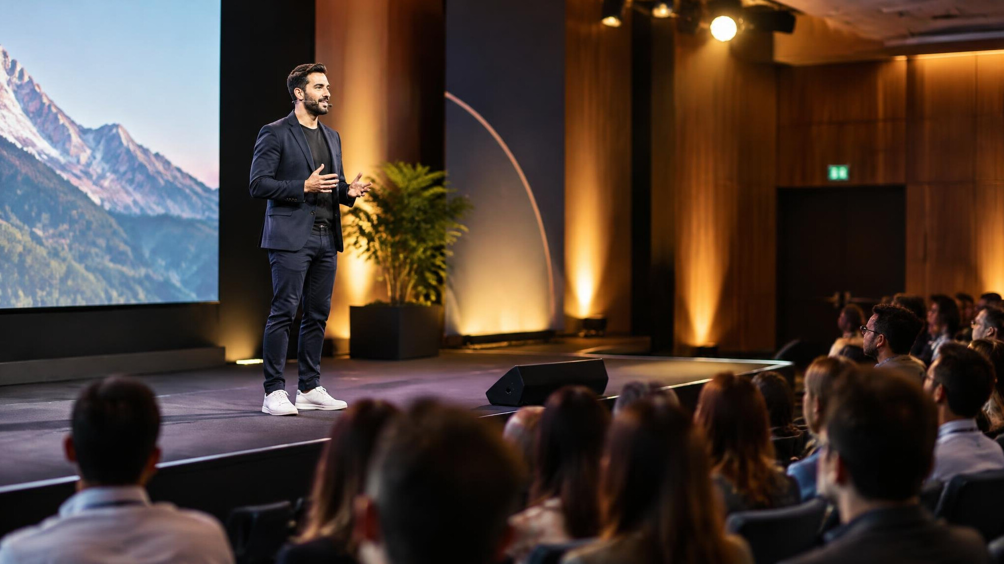 Speaker presenting on a conference stage in front of an audience